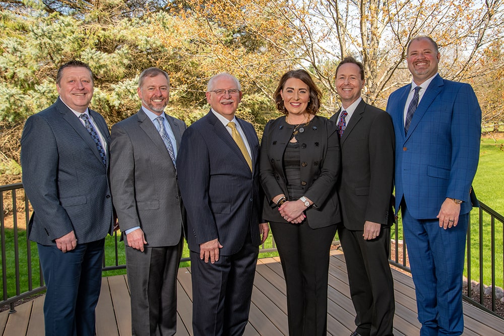 The Schaeffer Group team standing in a row outside on a deck. Gregory Schaeffer, Kristi Schaeffer, Edward Burnett, William Waddle, Mark Salerno, and Bradley Potter